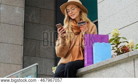 Millennial Girl Making Online Shopping Using Phone And Credit Card Nods Head Affirmative Female Cust