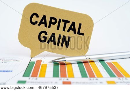 Business Concept. On The Financial Charts Lies A Pen And A Sign With The Inscription - Capital Gain