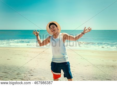 Portrait Of Man In Hat On The Beach Spreading His Arms. Smiling Young Man On The Beach Spreading Arm