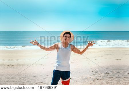 Concept Of Man Enjoying The Beach. Portrait Of Man In Hat On The Beach Spreading His Arms. Smiling Y