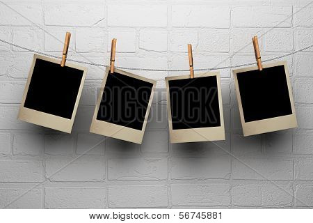 Photos Hanging On Clothespegs Against A Wall