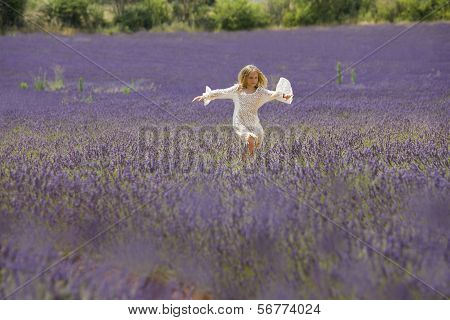 Beautiful young girl jumps in the middle of a lavender field