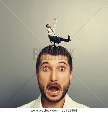 portrait of scared man with small crazy man on the head