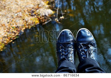 Black Sneakers Shoes Against Water In Nature
