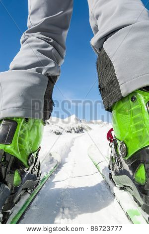 Close Up Of Skier's Boots And Skis From Ground Level.