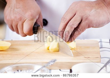 Chef Cutting Potato On Wooden Broad
