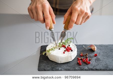 Woman's Hands Using Cheese Knife And Fork To Cut Camembert
