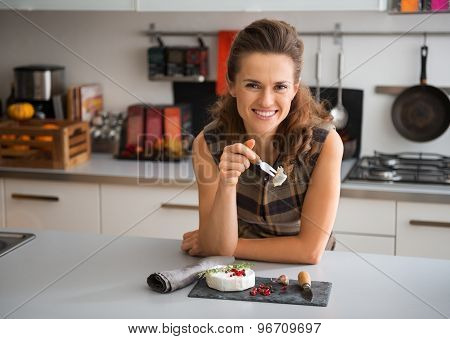 Smiling Woman Leaning On Counter Having Camembert Cheese