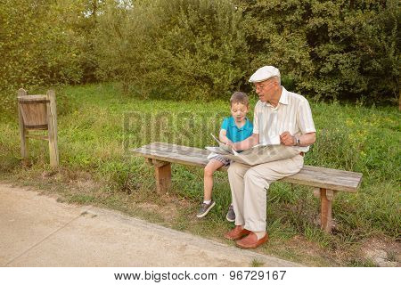 Senior man and child reading a newspaper outdoors
