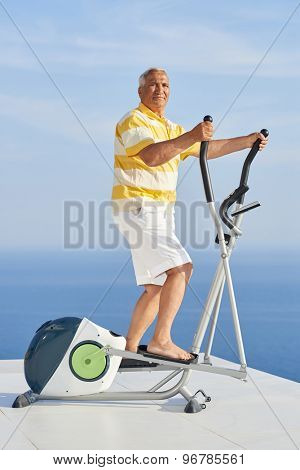 healthy senior man working out on gym treadmill machine at modern home terace with ocean view