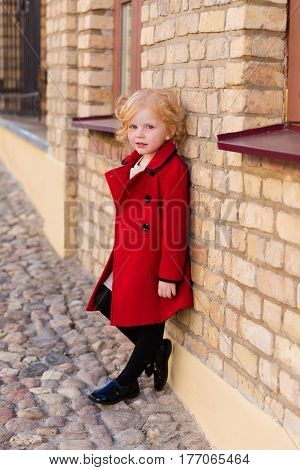 Portrait Of A Beautiful Little Girl With Red Hair In A Red Coat