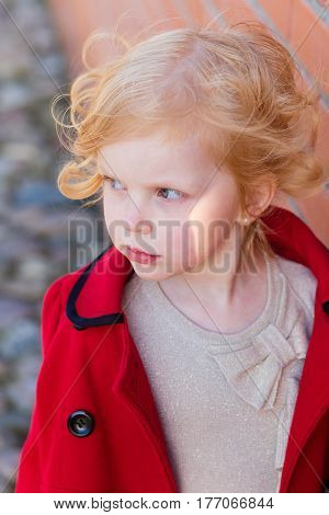 Portrait Of A Beautiful Little Girl With Red Hair In A Red Coat