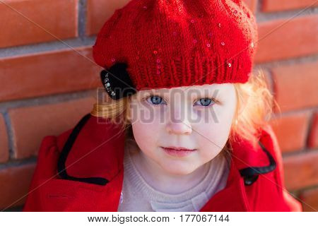 Portrait Of A Beautiful Little Girl With Red Hair In A Red Coat