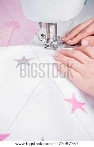 Woman's hands with dress at sewing machine close up