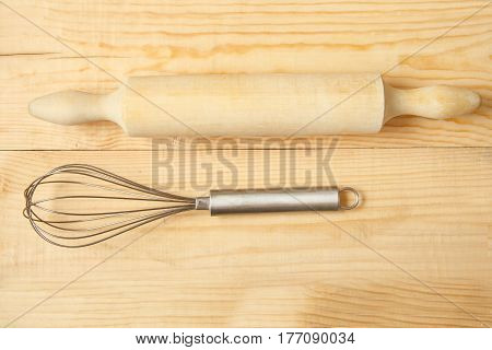 rolling pin and whisk on wooden table