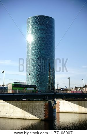 The modern glass facade of the Westhafen Tower in the sunlight and behind the peace bridge.