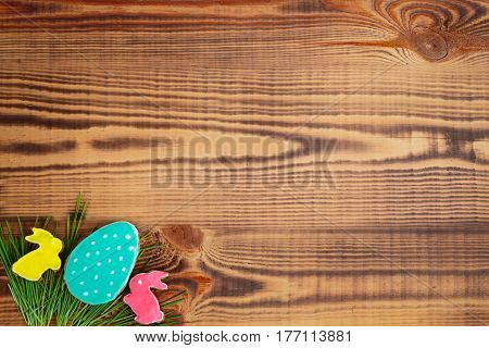 Happy easter. Easter background. Easter cookies. Gingerbread in the form of colored Easter rabbits and eggs on green grass on a background of brown wooden desk. Free space