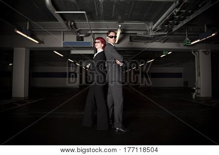 mafiosi couple posing in a car park