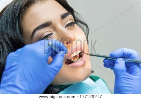 Young female at the dentist. Concave dental mirror.