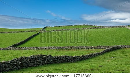 Hill of farm fields in the Terceira island in Azores with blue sky and clouds