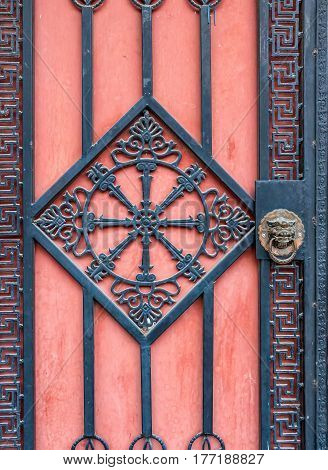 Beijing, China - Oct 30, 2016: Modern iron gate with oriental design comes with a traditional lionhead brass knocker. Image captured from a street in Old Beijing.