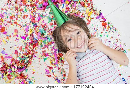 Young boy blows out confetti, isolated on white background