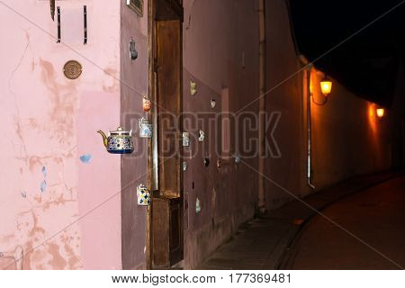 Vilnius Lithuania - August 7 2012: Vintage ceramic teapots embedded in facade corner of historic building on main street of old town. Inscription on kettle indicates address Bernardine street