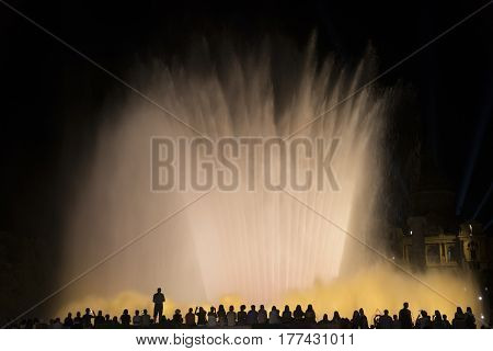 BARCELONA, SPAIN - JULY 30, 2016: Barcelona (Catalunya Spain): the Magic Fountain (Fuente Magica Font Magica) of Montjuic with plays of colorful lights at evening and people in silhouette watching at the show