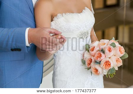 Young wedding couple hold each other on by hands and walking together, bride with wedding bouquet