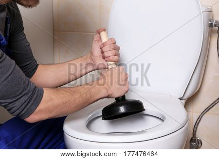 Plumber repairing toilet with hand plunger