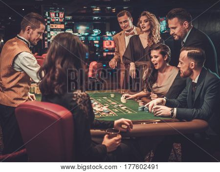 Upper class friends gambling in a casino.