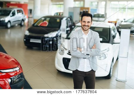 Handsome salesperson at car dealership selling vehichles