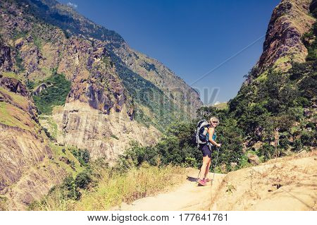 Woman backpacker climbing with backpack in Himalayas Nepal. Trekking and hiking with backpack in high mountains. Annapurna Himal Range on Annapurna Circuit Trek. Autumn season in Nepal Asia.