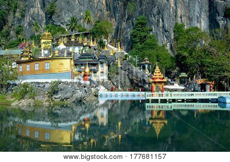 Bayin Nyi (Begyinni) Complex in Hpa-An Myanmar. Buddhist monastery and lots of golden stupas reflecting in the water of the sacred lake.