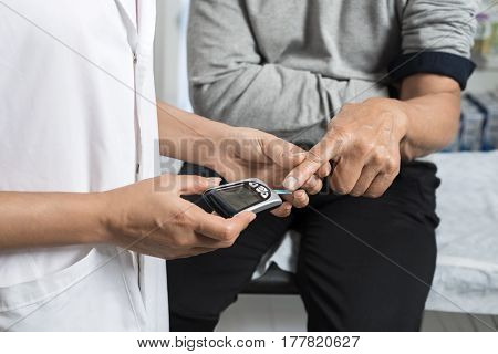 Female Doctor Examining Sugar Level Of Patient With Glucometer