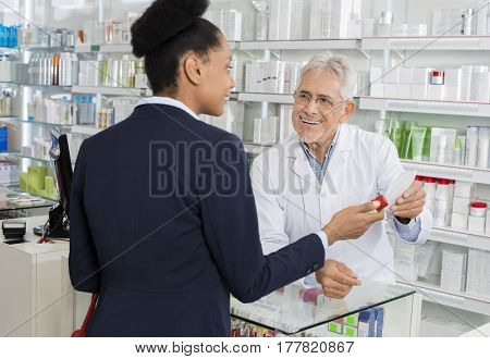 Chemist Holding Prescription Paper While Looking At Businesswoma