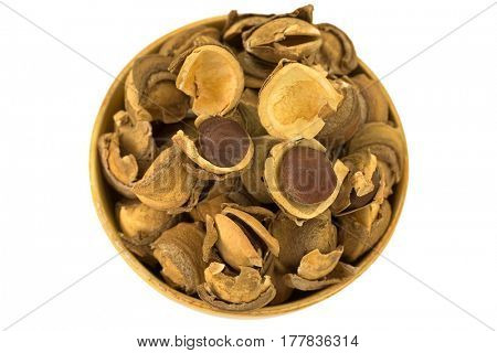 Closeup of seed and shell covers of Sacha inchi peanut, capsult fruit nut in a wooden bowl isolated on white background (Plukenetia volubilis)
