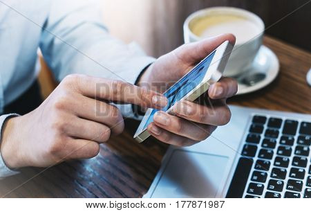 Girl pointing finger smartphone hipster using open laptop with empty blank monitor screen in office cup of coffee on background bokeh of light in cafe female hands texting on mobile mockup blur