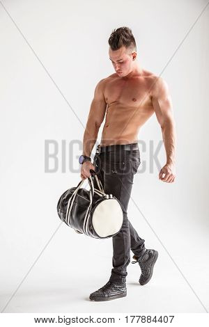 Sexy muscular man body posing at white wall, black jeans