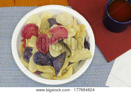 Three different colors of potato chips with tomato juice. Colorful red white and blue chips made from Crimson Purple Majesty and Chipeta or Atlantic potatoes.