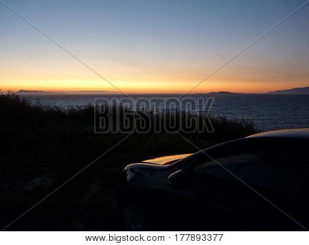 Sunset over the sea and the car on a high bank, Peroulades, Corfu, Greece, the Adriatic, the Mediterranean Sea