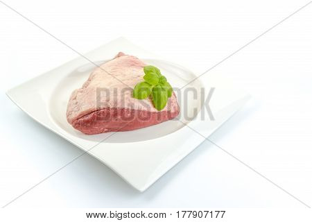 Full Piece Of A Fresh Raw Cow Beef (picanha) And Basil Leaves On A White Dish With White Background
