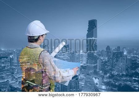 Double exposure Construction engineer checking construction drawing with modern cityscape for new Infrastructure construction project concept