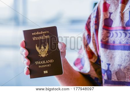 Hand holding Thai passport at the airport