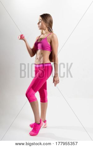 Woman In Sportswear Is Engaged In Fitness. In The Hands Holding Dumbbells. Photo Studio.