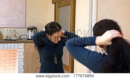 Beautiful brunette woman drying long black silky hair and smartens up in front of mirror in make-up dressing room.