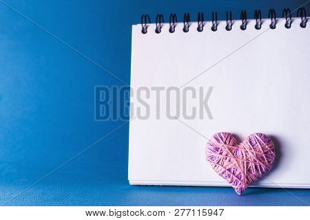 Simple Blue Background With A Small Purple Red Heart Yn Notebook. Place For Text