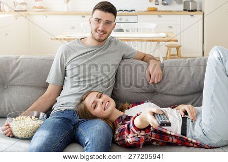 European Man And Woman Watching Tv Together At Home, Femaly Lying On Boyfriend's Knees While He Is H
