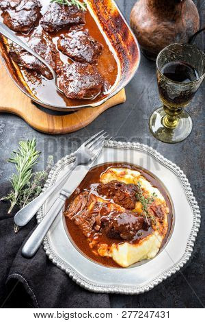 Traditional German braised veal cheeks in brown sauce with mashed potatoes as top view on a pewter plate 