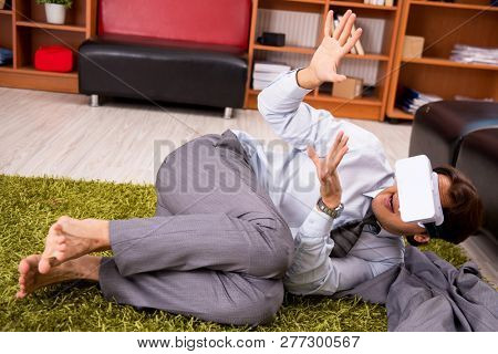Young employee with virtual glasses during break in the office 